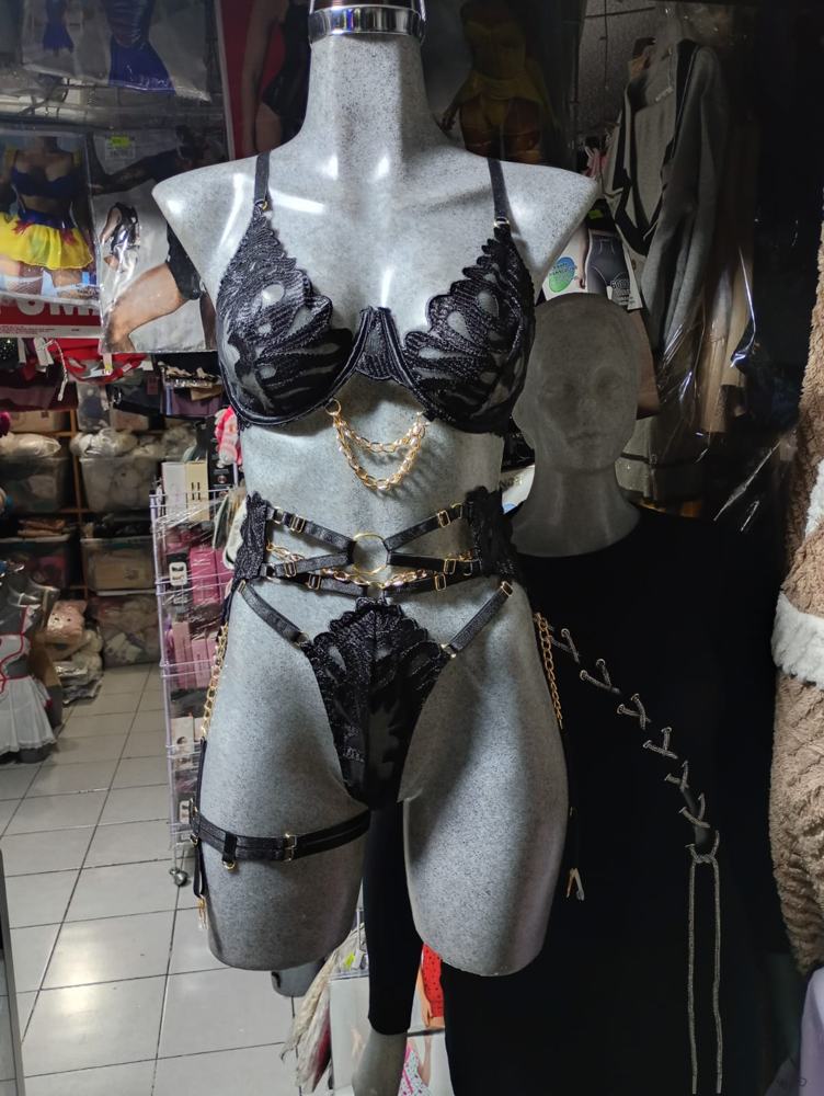 Conjunto negro de tres piezas con cadenas doradas en el maniquí
